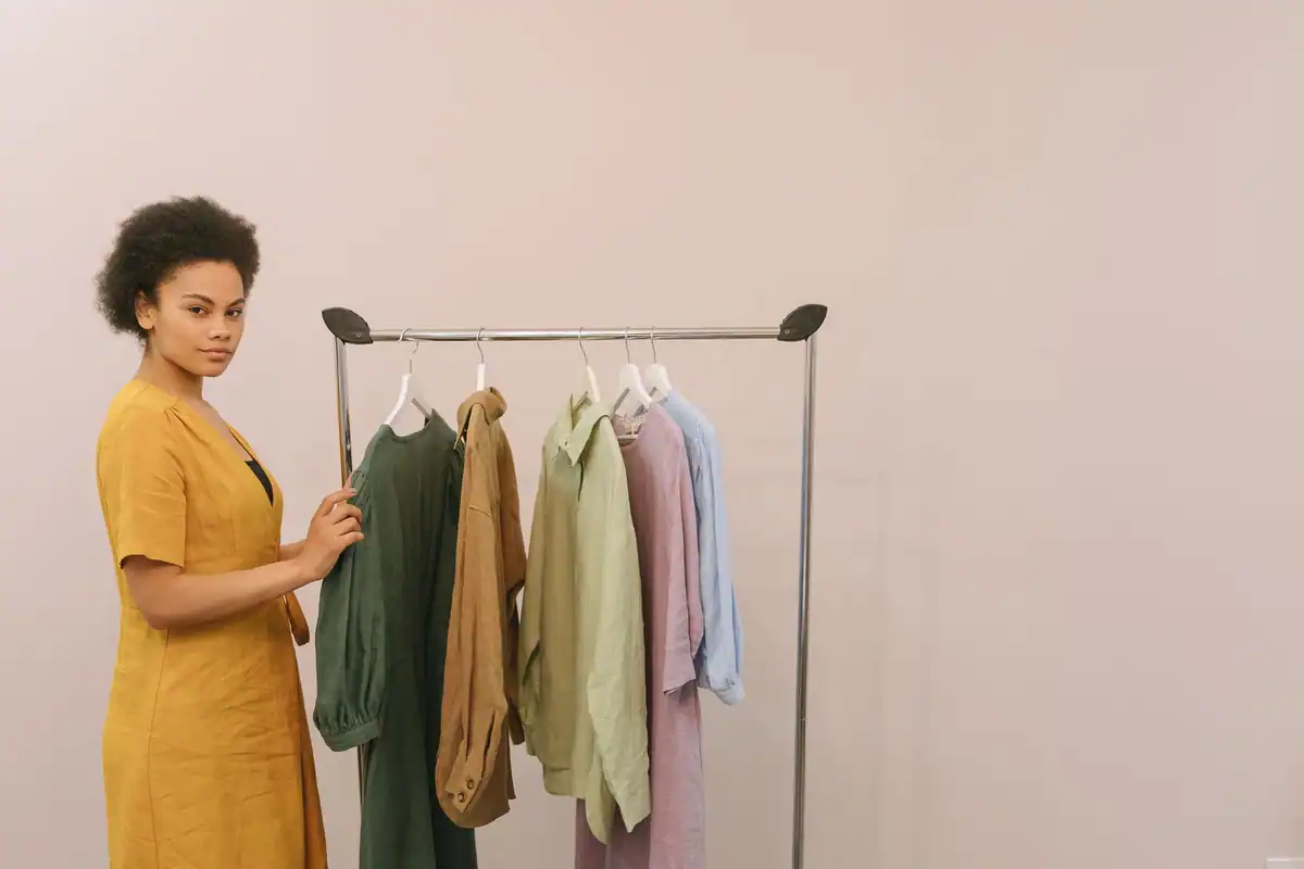 Femeie într-un magazin de haine care analizează atent piesele colorate de pe stand