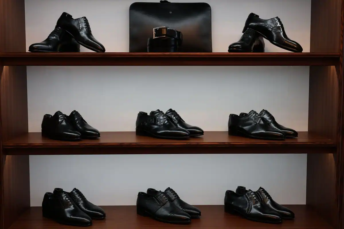 Pantofi negri din piele și accesorii asortate expuse pe rafturi de lemn