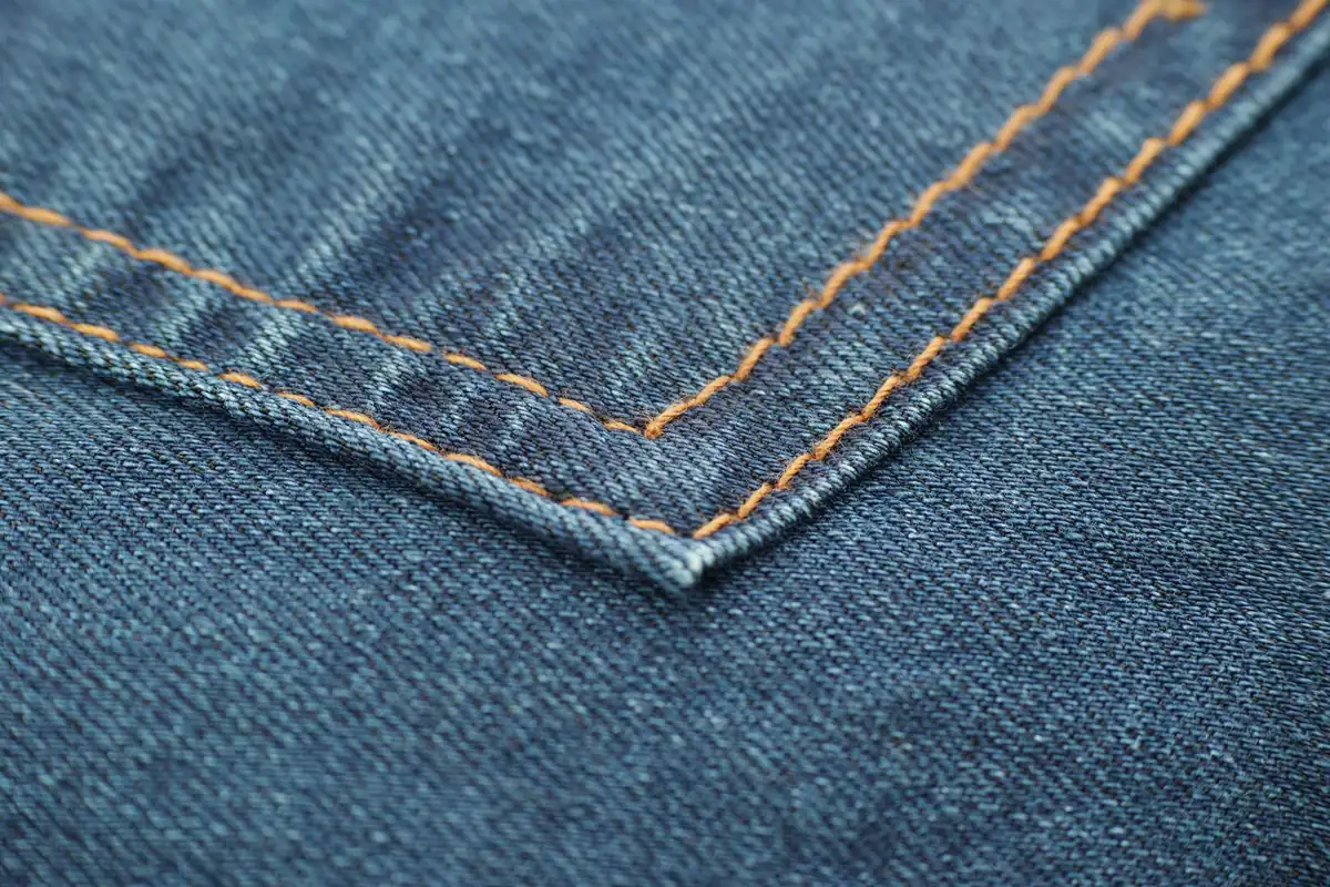 Cusături fine pe o țesătură denim albastră văzute în prim-plan