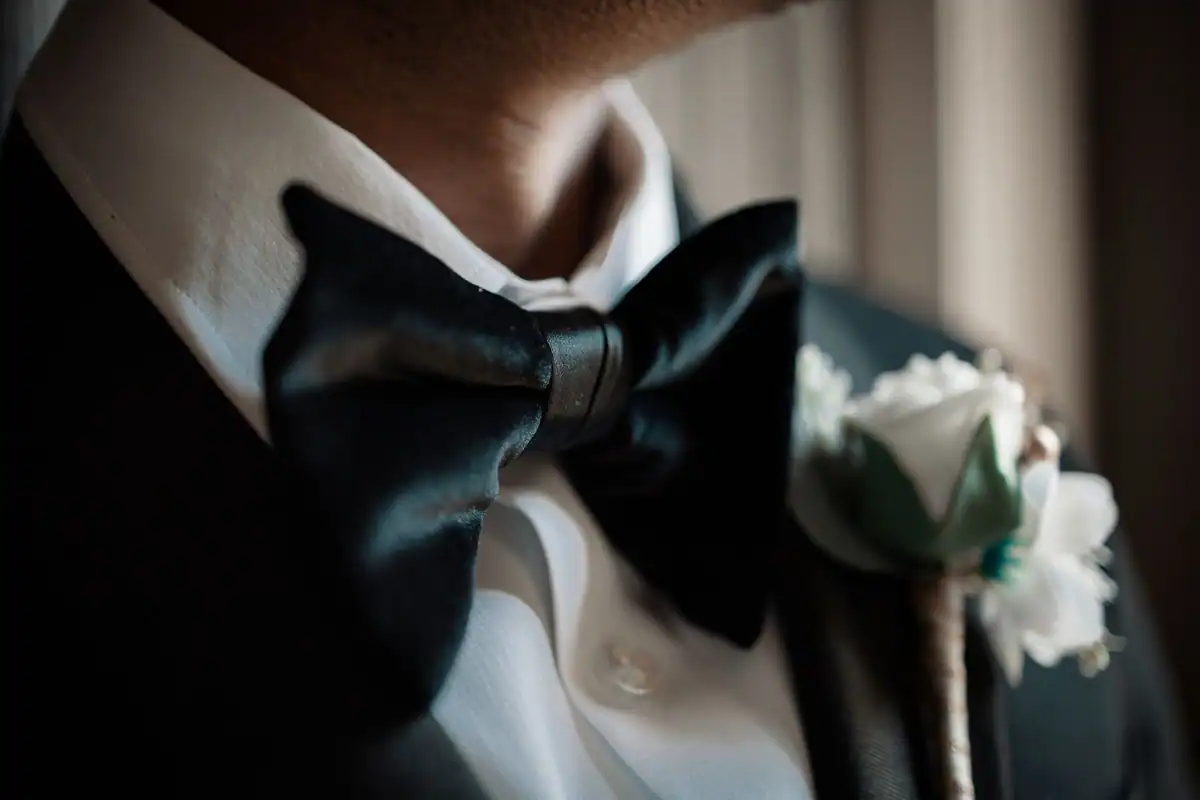 Papion negru și floare la reverul unui smoching, ținută black tie la nuntă