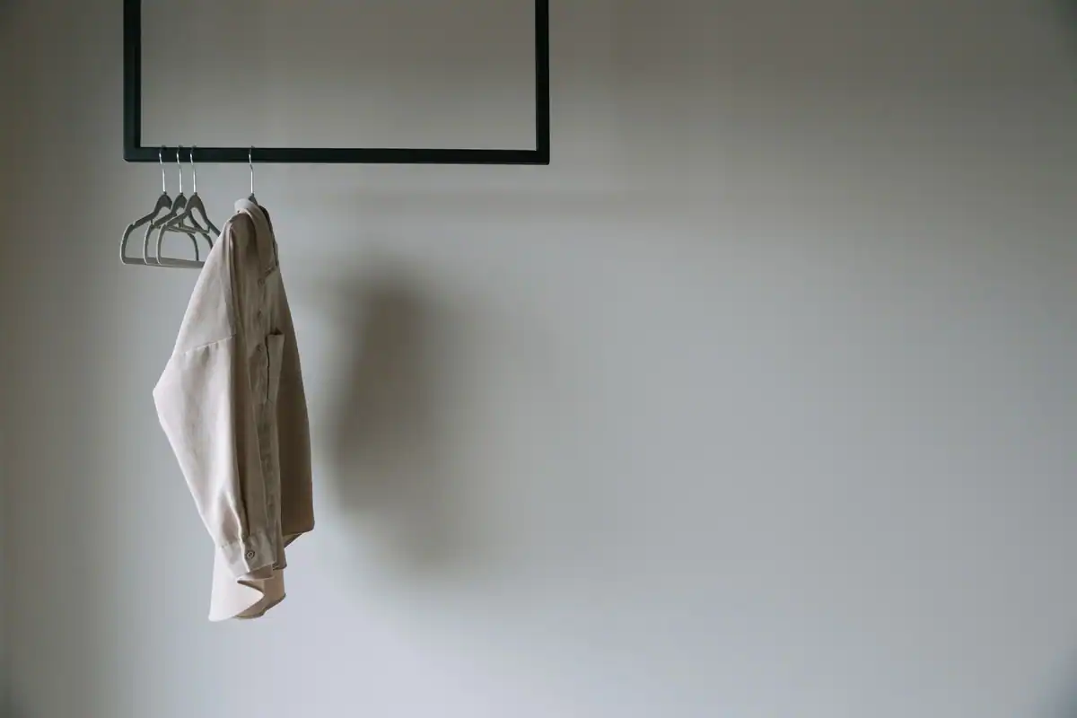 Sacou bej atârnat pe un stand metalic minimalist, piesă de bază a garderobei