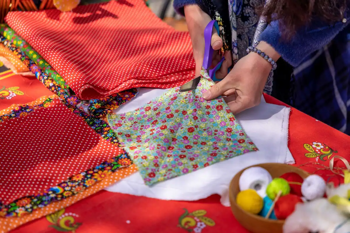 Țesături colorate cu imprimeuri diferite tăiate cu foarfeca pe masa de lucru