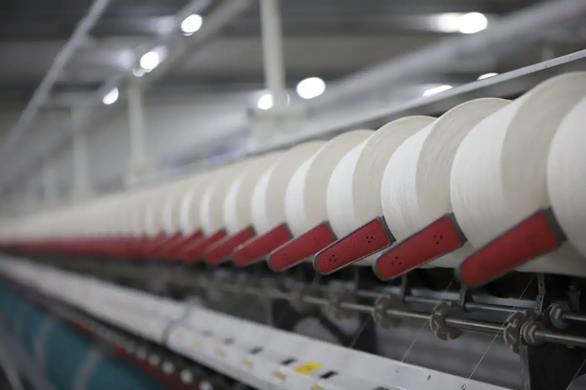 Bobine de fir alb pe o linie de producție dintr-o fabrică textilă