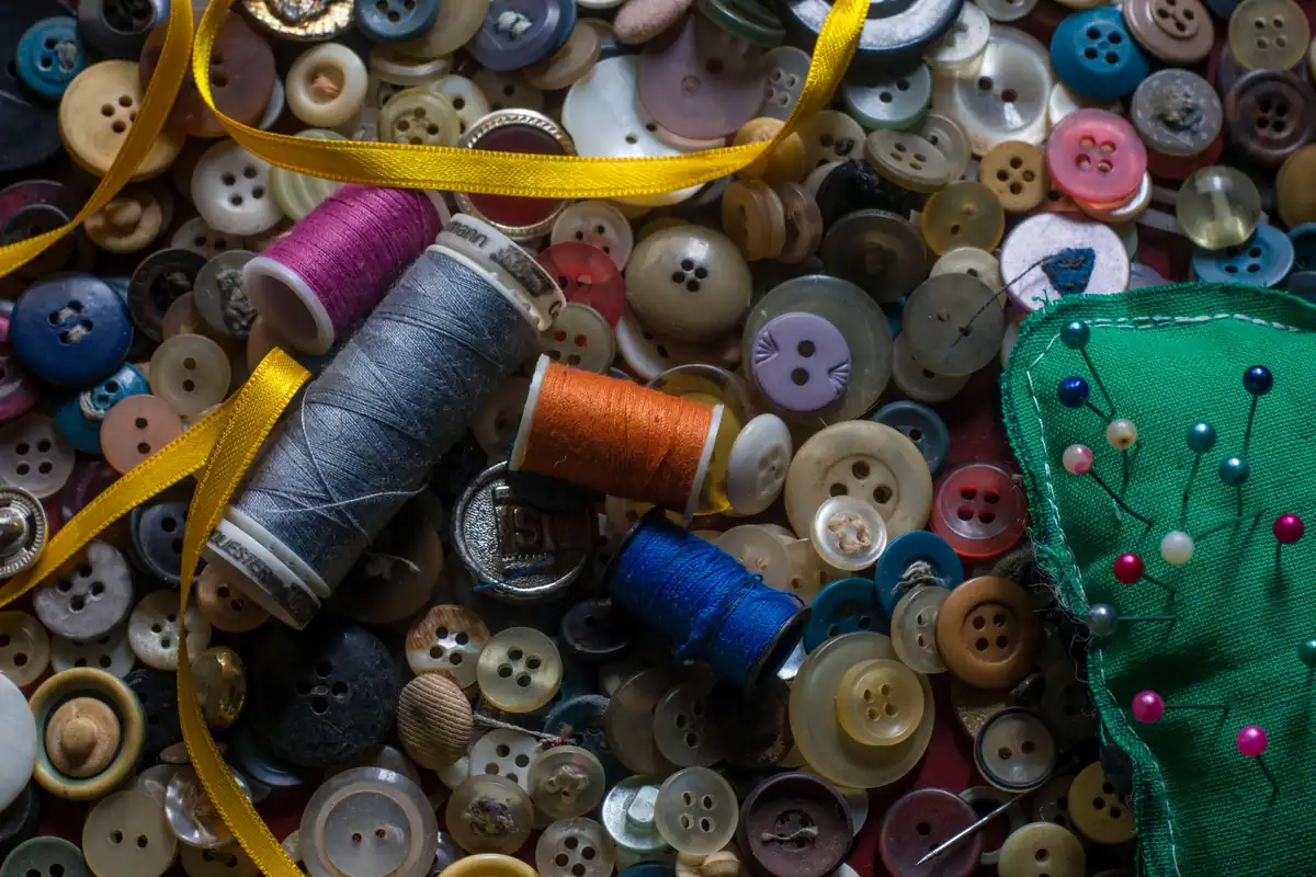 Bobine de ață, nasturi colorați, ace și panglică pentru reparații la haine
