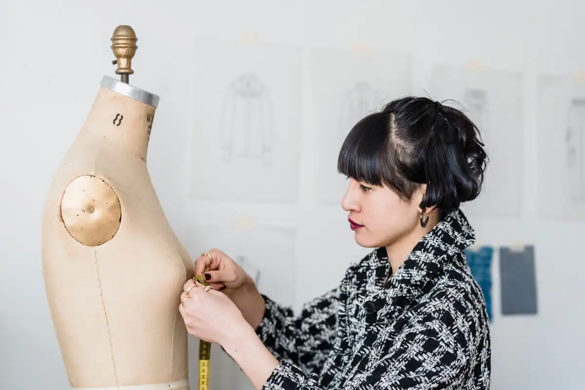 Creatoare de modă care ajustează o rochie pe manechin în atelier